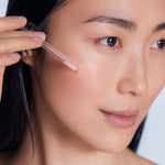 Model applying BL+ The Serum to face using dropper
