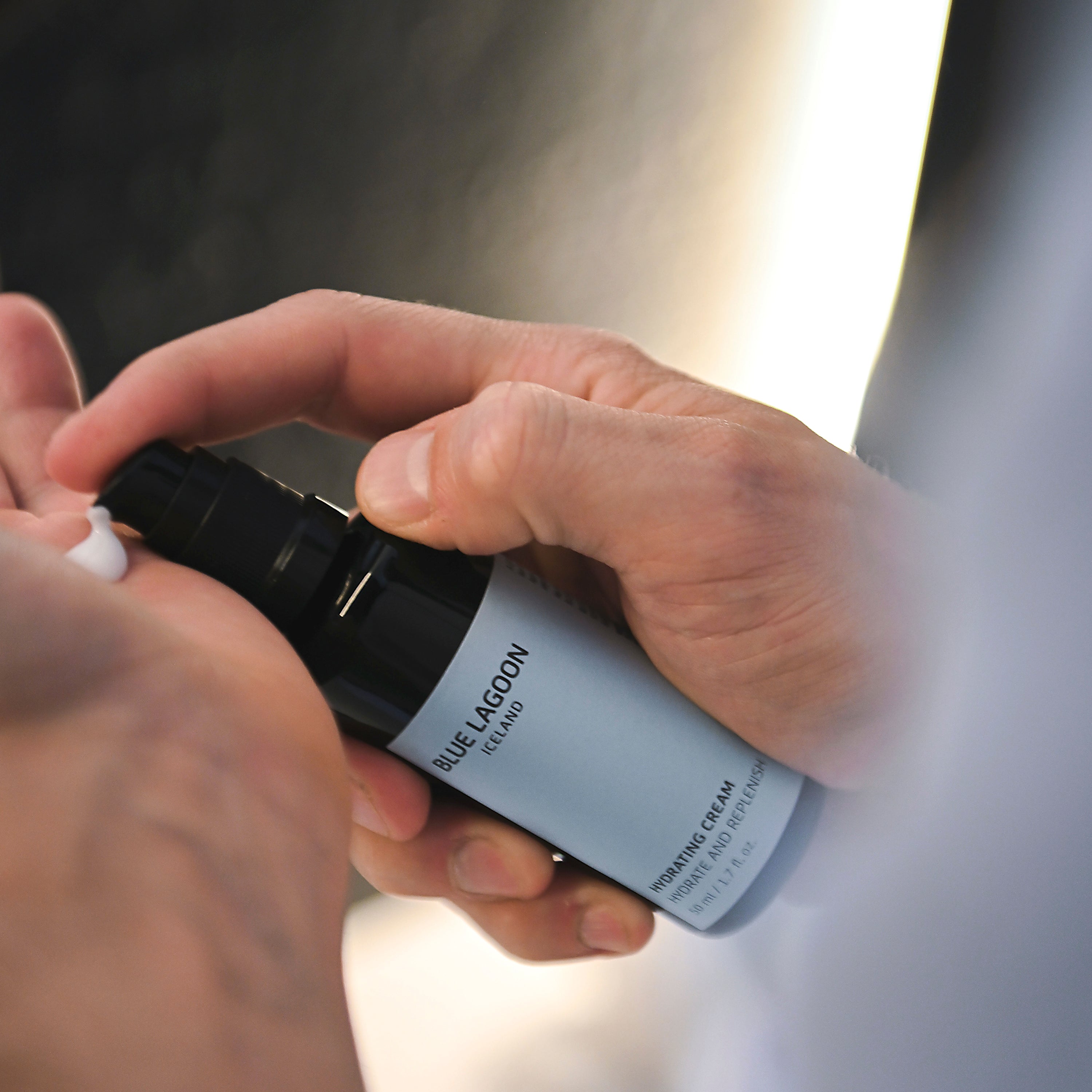 Model dispensing Hydrating Cream from pump into hand