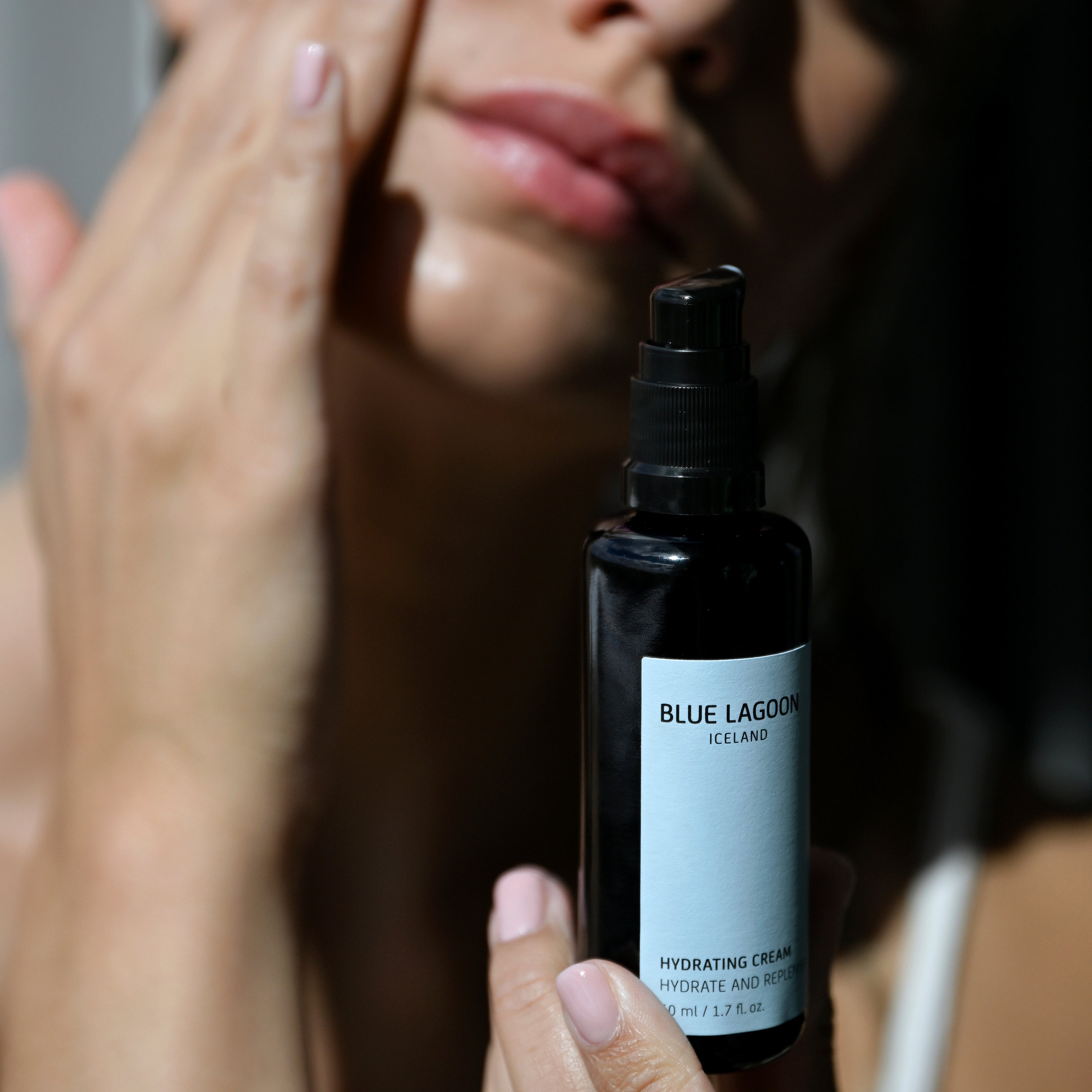 Model applying Hydrating Cream to face from pump bottle”