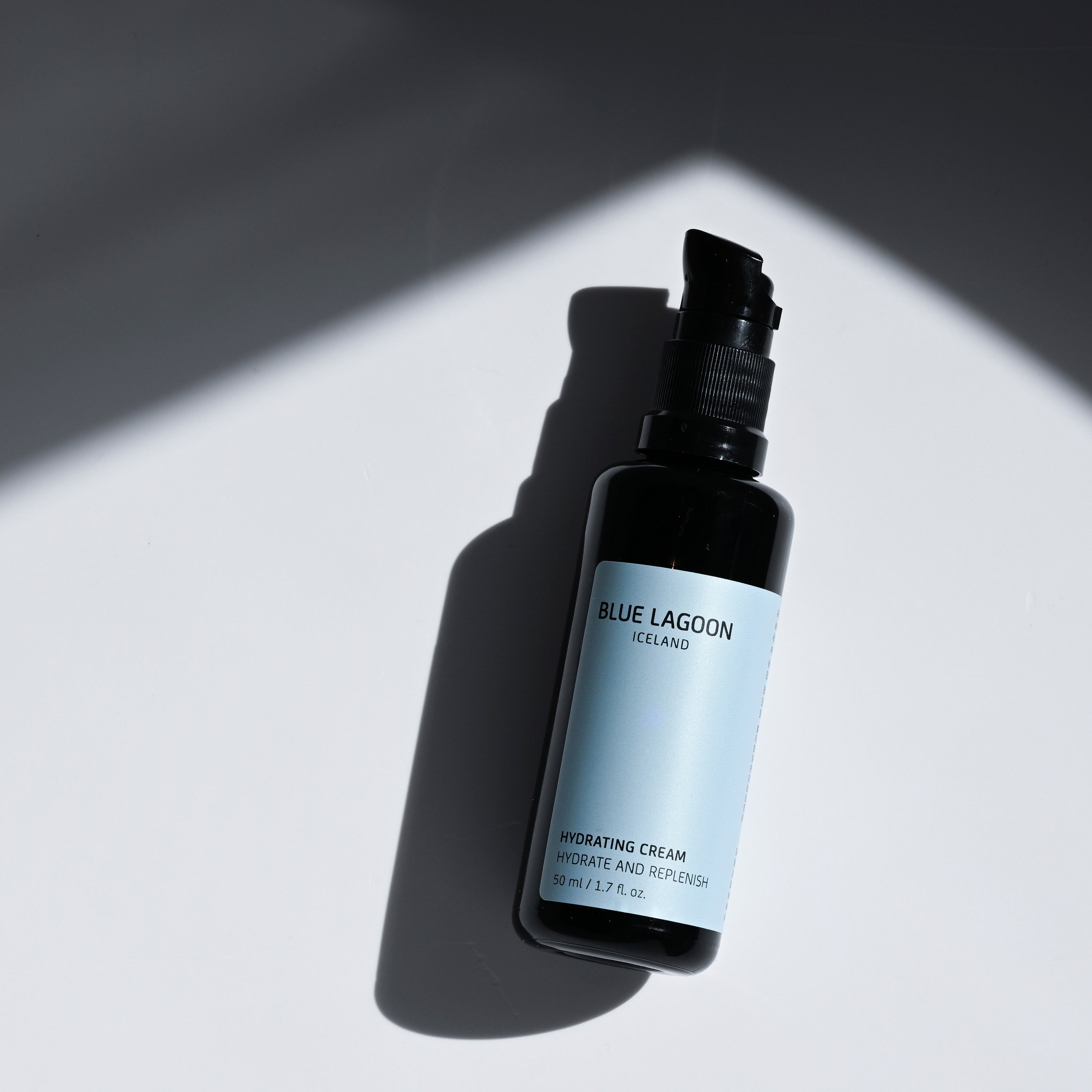 Hydrating Cream bottle with pump on light surface with shadow