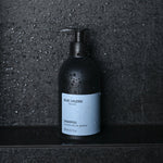 Shampoo bottle standing on wet stone surface in shower setting