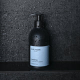Shampoo bottle standing on wet stone surface in shower setting