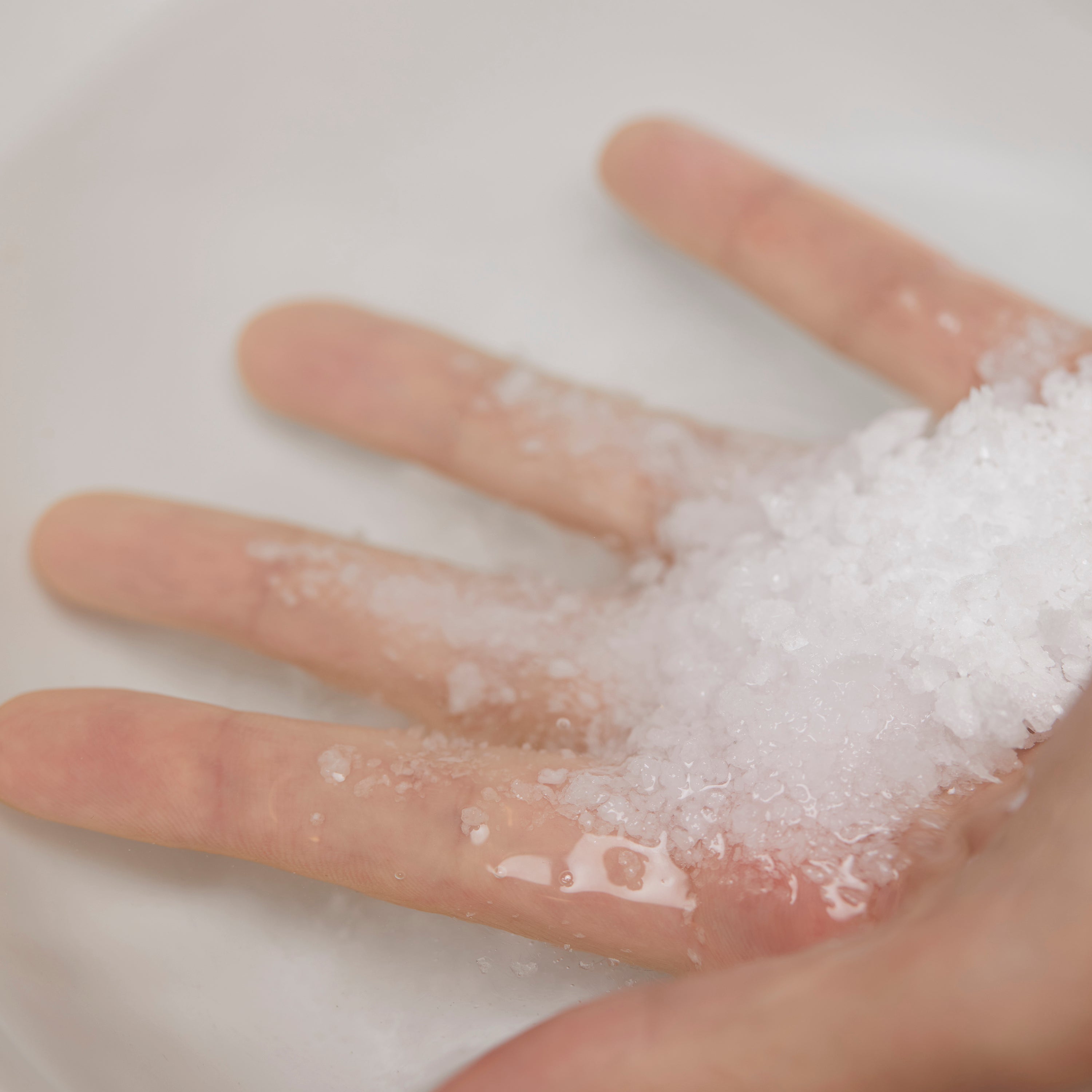 Hand showing texture of Mineral Bath Salt showing coarse white salt crystals