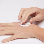 Model applying Mineral Intensive Cream to the back of the hand, showing creamy texture and spreadability